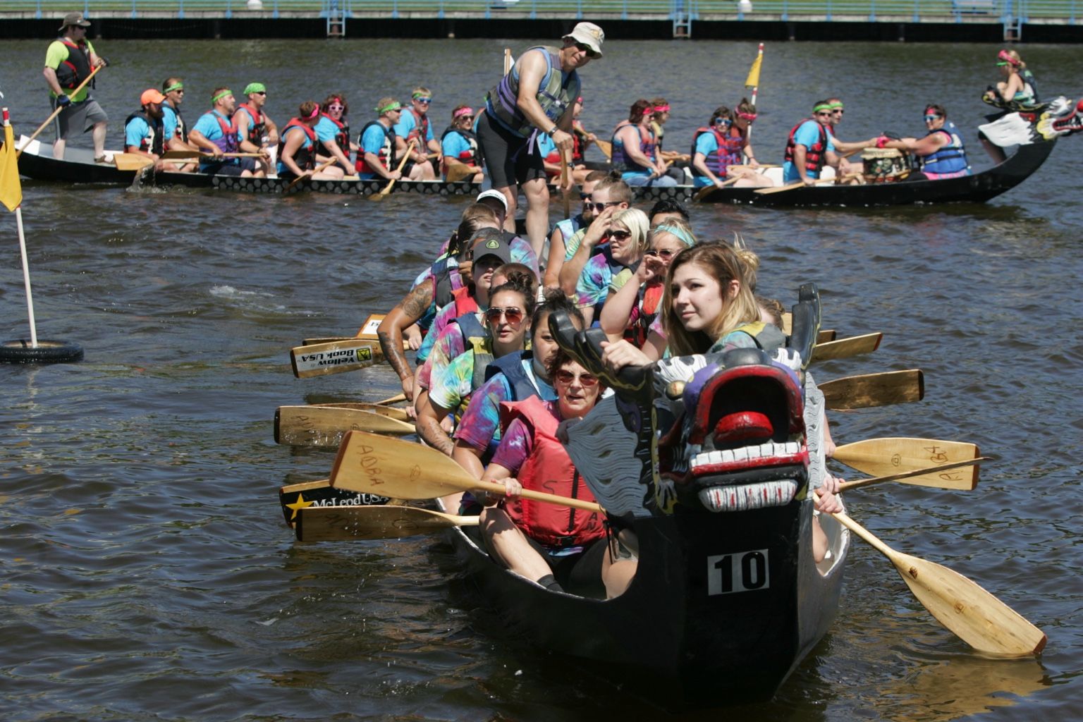 A crowded dragon boat crew paddling together on the Sheboygan waterfront.