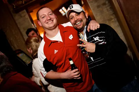 Two buddies, one in a Badgers shirt, beers up at Mojo's.
