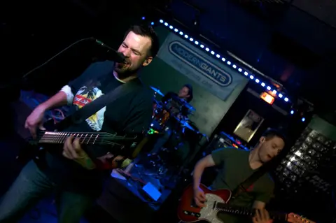 A band playing under blue stage light at Sandees.