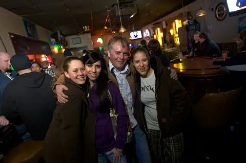 Winter-coat crowd posing arm-in-arm under the bar lights at Vreekes Bar.