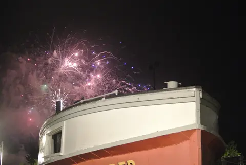 Fireworks bloom over a boat hull.