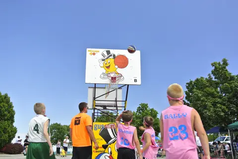 Street-court 3-on-3, with a top-hatted basketball mascot painted on the backboard.