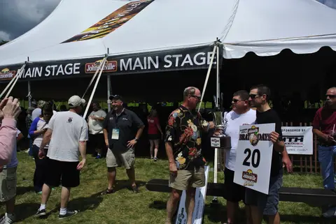 Trophy time at the Main Stage tent, bracket card No. 20 held high.