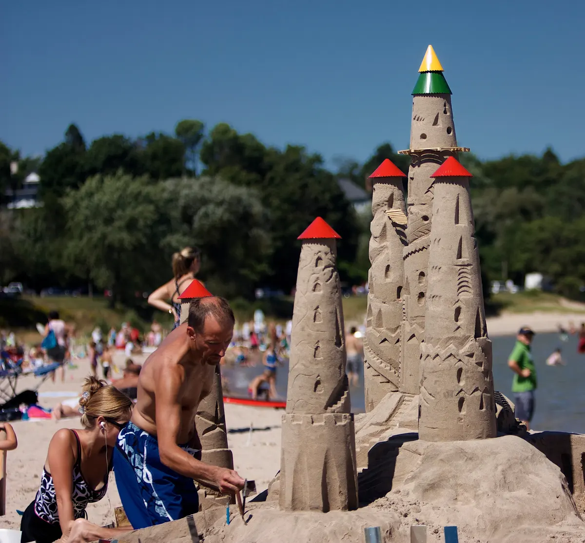 Sandcastle towers going up at the Dairyland Surf Classic, beachgoers and Lake Michigan behind.