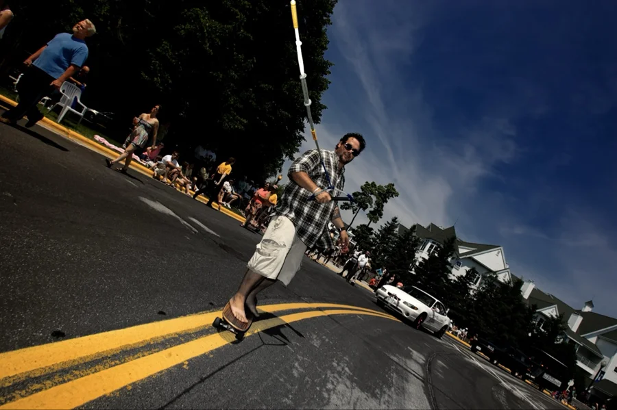 Barefoot skateboarder with a sail rig on the parade route
