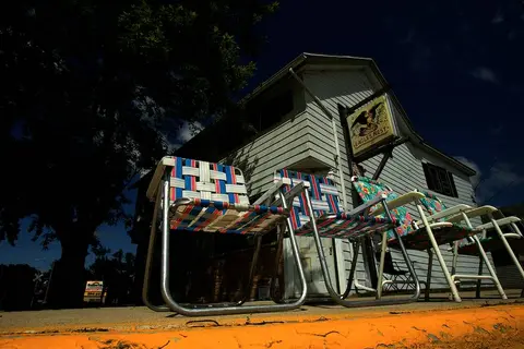 Night exterior of a small building with a rooftop sign and lawn chairs out front, Random Lake.