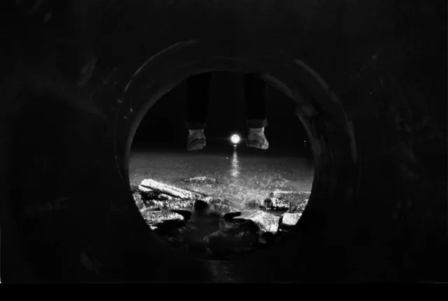 Black and white night photograph looking through a pipe on the Sheboygan lakefront